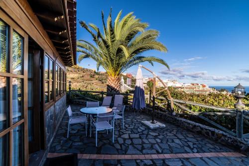 a patio with a table and chairs and a palm tree at CASA RURAL EL LAGAR TENERIFE in La Orotava