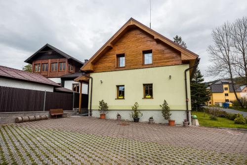 a house with a wooden roof on a brick driveway at Penzion 103 in Železná Ruda