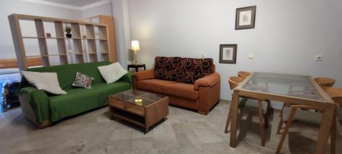 ein Wohnzimmer mit einem grünen Sofa und einem Tisch in der Unterkunft Apartamentos Serrallo, Parking gratuito y cocina, Alhambra y playa in Granada