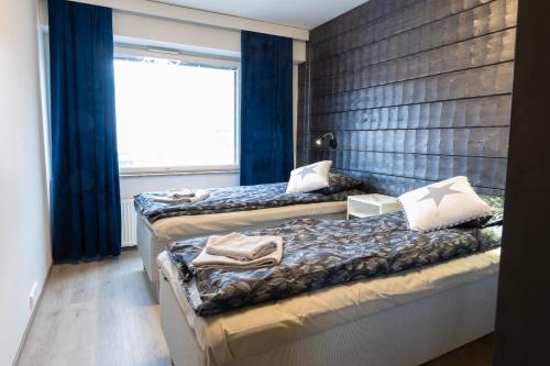 two beds in a room with blue curtains and a window at Apartment Rovakatu B12 in Rovaniemi