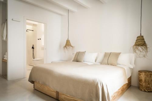 a white bedroom with a large bed and two pendant lights at Meloussa Boutique Hotel in Ciutadella