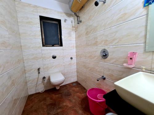 a bathroom with a toilet and a sink and a mirror at Fogg Villa - Valley View / Swimming pool / AC in Mahabaleshwar