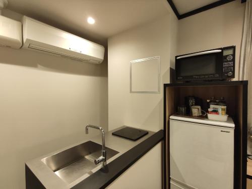a kitchen with a sink and a microwave and a refrigerator at yksi SAUNA & STAY in Tokyo