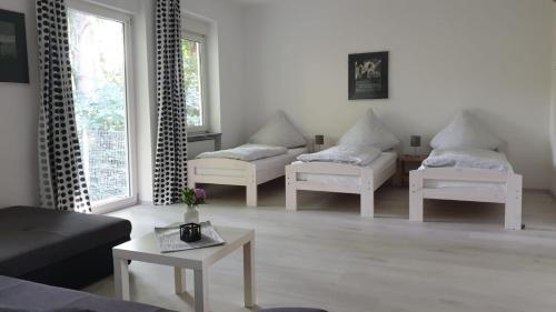 a living room with three white chairs and a table at Naturfreundehaus Gelsenkirchen in Gelsenkirchen