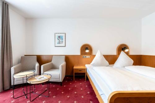 a hotel room with a bed and two chairs at Hotel & Gasthaus Löwen in Waldkirch
