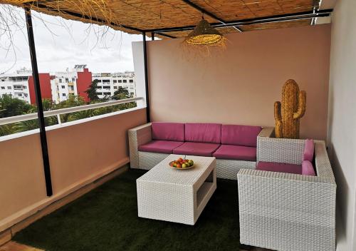 Sala de estar con sofá púrpura y cactus en LAU 10 Appart Terrasse, en Rabat