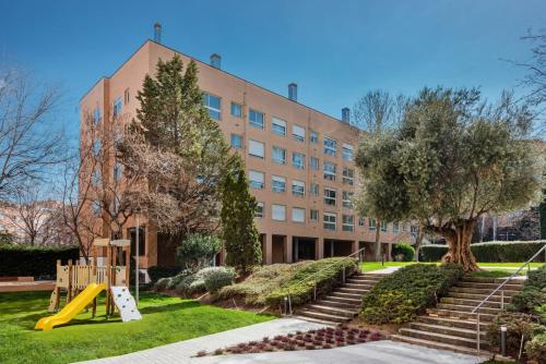- un bâtiment avec une aire de jeux en face dans l'établissement Los Castaños Design Apartments in Conde Orgaz Area, à Madrid