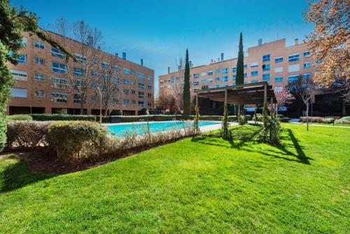 une piscine dans un parc en face d'un bâtiment dans l'établissement Los Castaños Design Apartments in Conde Orgaz Area, à Madrid