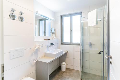 La salle de bains blanche est pourvue d'un lavabo et d'une douche. dans l'établissement Altstadthotel Grauer Wolf, à Erlangen