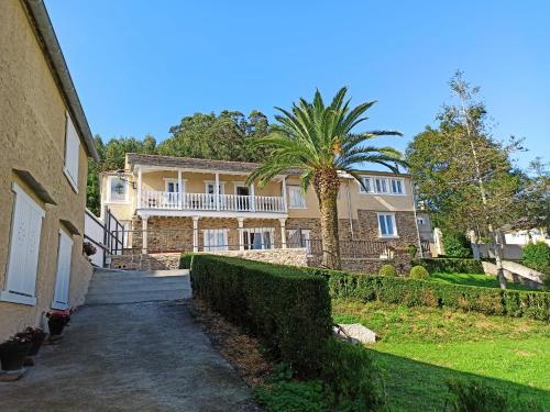 a large house with a palm tree in front of it at Apartamentos Minas de Silvarosa in Viveiro