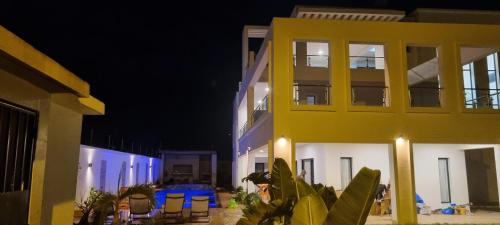 a building at night with chairs in front of it at Villa Bolati, avec piscine, jacuzzi, jardin et vue in Bonoua