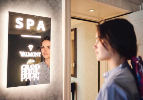 a woman looking at her reflection in a mirror at Grand Hotel du Lac - Relais & Châteaux in Vevey