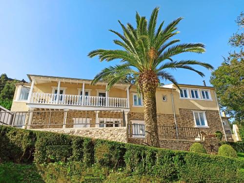 a palm tree in front of a house at Apartamentos Minas de Silvarosa in Viveiro