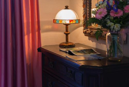 a table with a lamp on top of a dresser at Hotel San Valentino Terme in Ischia