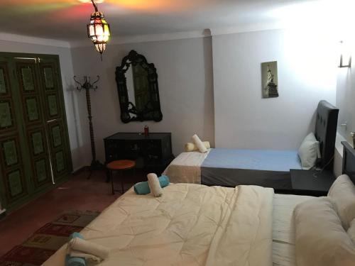 a bedroom with two beds and a couch and a mirror at Dar el Koutoubia in Marrakech