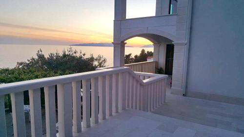 a balcony of a house with a sunset over the water at Apartments Villa Bella Vista in Gornji Dingač