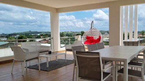 Bonoua的住宿－Villa Bolati, avec piscine, jacuzzi, jardin et vue，阳台的用餐室配有桌椅
