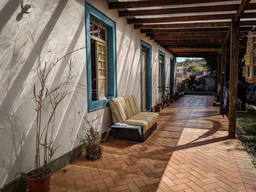 a porch of a house with a chair and a window at Del Mundo Hostel in São João del Rei