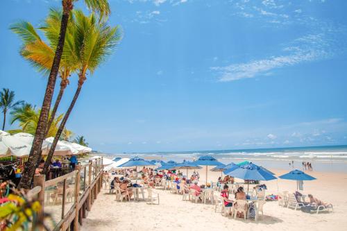 a crowd of people sitting on a beach with umbrellas at Jardim Atlântico Beach Resort in Ilhéus