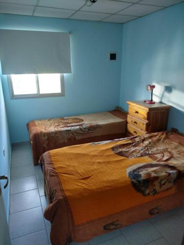 a bedroom with three beds and a dresser and a window at Departamentos Fuentes in Cipolletti