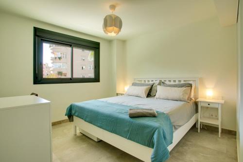 1 dormitorio con 1 cama con manta azul y ventana en Apartamento Sadio - Residencial Infinity en Estepona