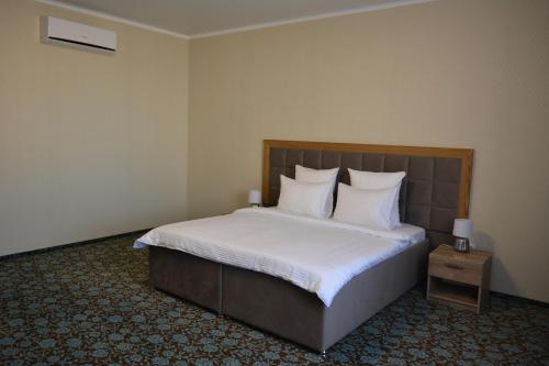 um quarto com uma cama com lençóis brancos e almofadas em Гостиничный комплекс "Коктобе" em Aqtöbe