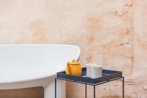 a side table with a yellow vase on it next to a tub at Cordyline Cottage - charming cottage, seconds from the beach in Kent