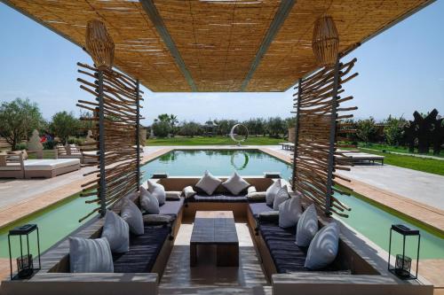 een patio met een zwembad en een grote houten pergola bij villa dar jad in Sehib Foukani
