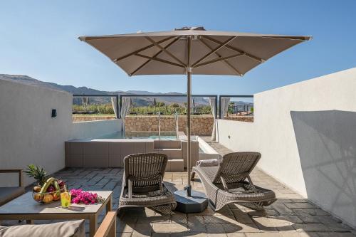 a patio with two chairs and an umbrella at Galini Palace in Kolymvari