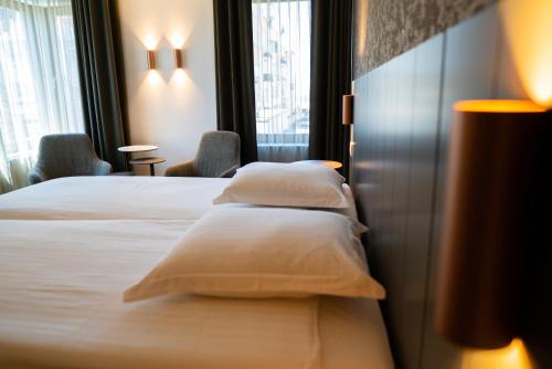 a hotel room with a bed and two pillows at Hotel Iris in De Panne