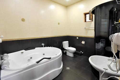 a bathroom with a large white tub and a toilet at Hotel Majestic in Tbilisi City
