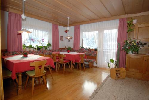 a dining room with red tables and chairs and windows at Bed & Breakfast Kranebitt in Eggen