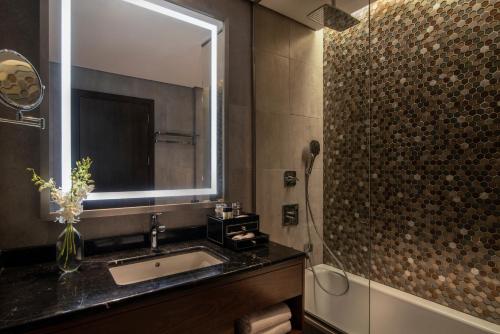 a bathroom with a sink and a mirror and a shower at Movenpick Hotel and Residences Riyadh in Riyadh