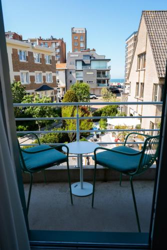 two chairs and a table on a balcony at Hotel Iris in De Panne