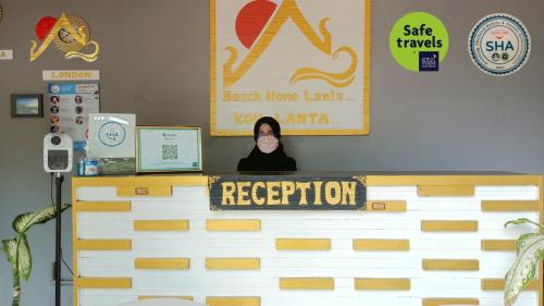 a person is peeking out from behind a counter at Beach Home Lanta in Ko Lanta