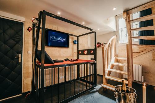 Cette chambre dispose de lits superposés, d'une télévision et d'un escalier. dans l'établissement LOVE ROOM Bordeaux Playroom avec salle de jeux pour adultes et lit à eau chauffant, à Bordeaux