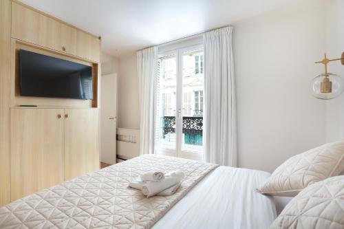 - une chambre avec un lit blanc et une télévision dans l'établissement Residence in the center of Paris by Studio prestige, à Paris