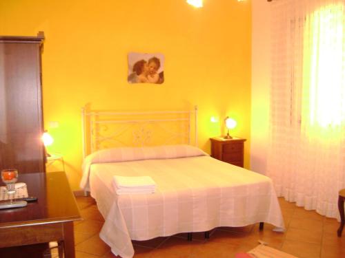 a bedroom with a white bed and a yellow wall at B&B Maria Paola in Castelluzzo