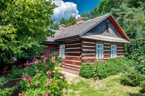 a small wooden house with flowers in front of it at Grenlanda in Ulanów