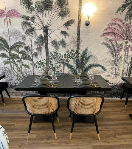 a black table with two chairs and a wall with palm trees at Le Domaine de Moroges in Moroges