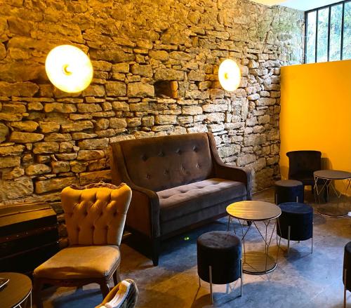 a living room with a couch and tables and a stone wall at Le Domaine de Moroges in Moroges
