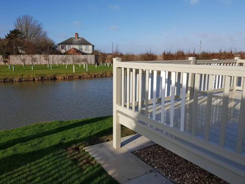 a white bridge over a river with a house in the background at 8 BERTH DELUXE CARAVAN ML88 GOLDEN PALM CHAPEL ST LEONARDs in Chapel Saint Leonards