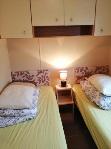 a room with two beds and a lamp on a table at 8 BERTH DELUXE CARAVAN ML88 GOLDEN PALM CHAPEL ST LEONARDs in Chapel Saint Leonards
