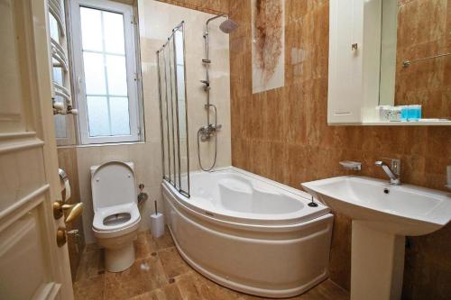 a bathroom with a tub and a toilet and a sink at Sanata in Tbilisi City