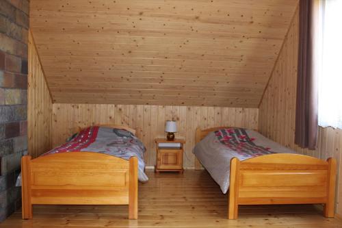 2 camas en una habitación con paredes de madera en Domek Pod Wierzbą, en Sikorzyno