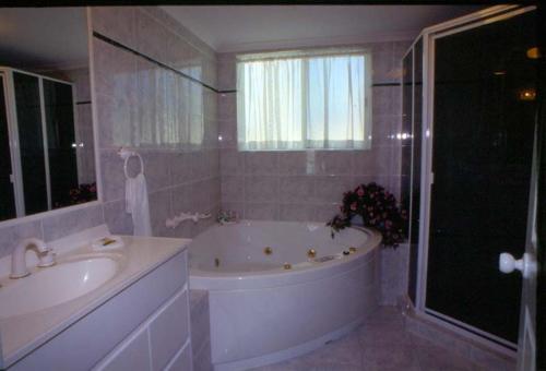 a bath tub sitting next to a window in a bathroom at Runaway Bay Motor Inn in Gold Coast