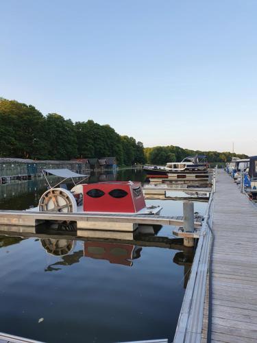 un barco rojo sentado en un muelle en el agua en Lütt Hütt, en Rechlin