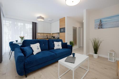 a living room with a blue couch and a table at Klifowa Premium Resort with SPA, Fitness & Kids Club by Renters in Rewal