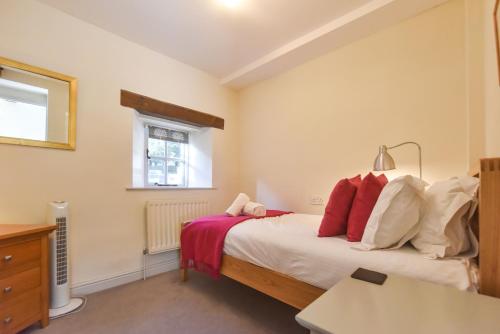 a bedroom with a bed with red pillows at Church Farm Holiday Cottages - Pinster Cottage in Ashbourne