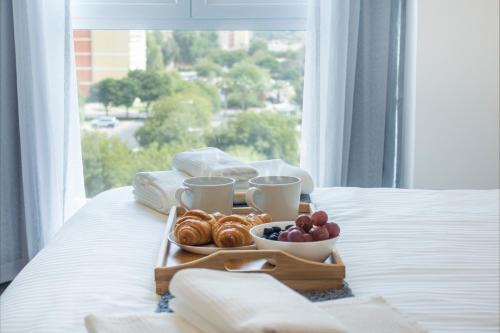 a tray of breakfast food on a bed with a window at LUXE Studio Near Discovery Gardens Metro Station in Dubai